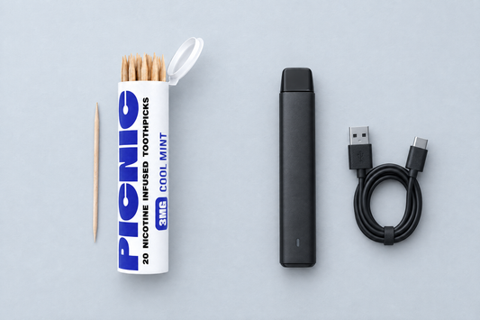 A Picnic nicotine toothpick tube next to a switched-off unbranded vape device on a desk